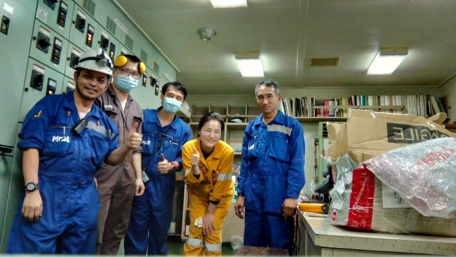 A Moim surveyor with the crew of a vessel during an audit, photographed in the engine control room.